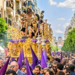 El paso de Cristo de Las Cigarreras a su paso por la calle Asunción, con la Portada de la Feria de Abril al fondo, este jueves Santo en Sevilla. EFE/ Raúl Caro