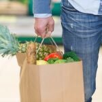 Bolsa de papel cargada de fruta y verdura en un supermercado.