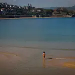 Una mujer pasea por la orilla de la playa de La Concha de San Sebastián.