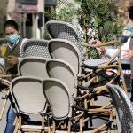 Un camarero y una camarera trabajan montando la terraza de un local en el centro de Valencia