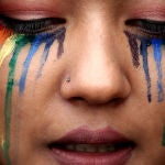 Una persona del colectivo LGTBIQ+ con la bandera arcoíris en su rostro