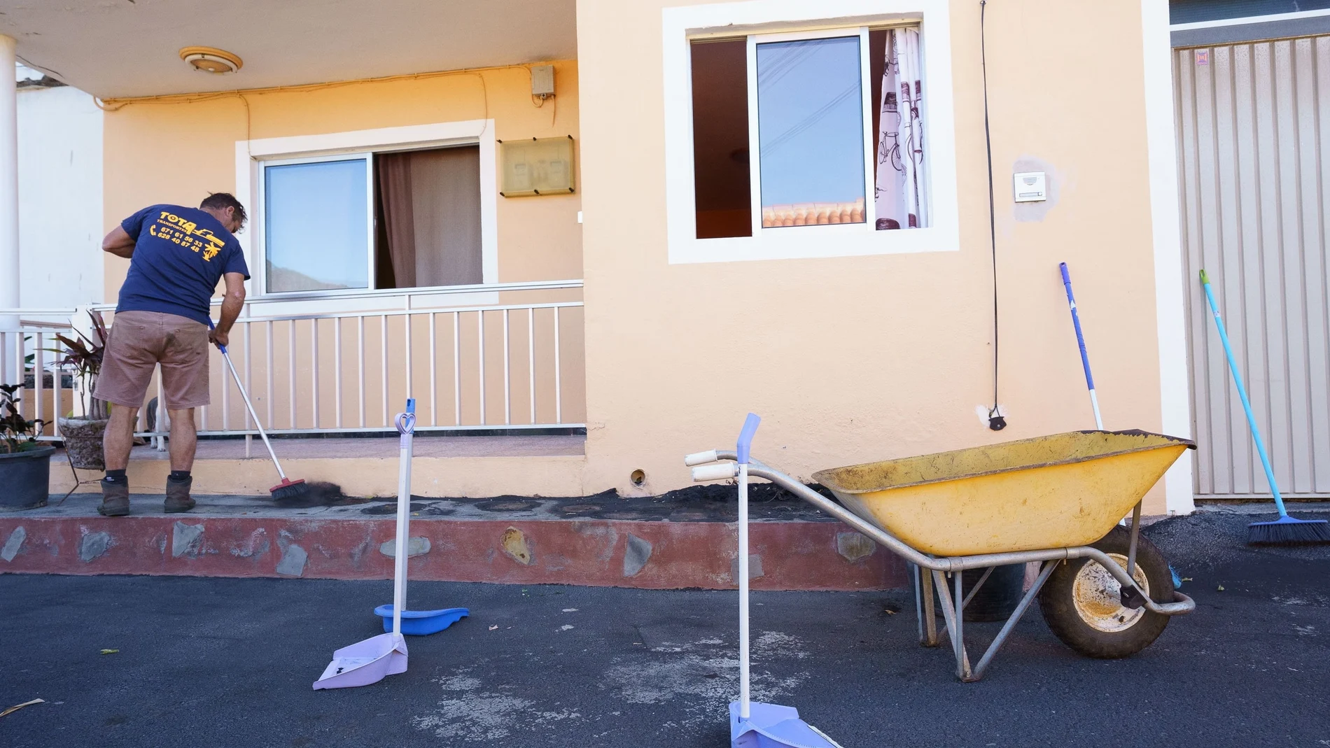 Un hombre limpia de ceniza volcánica el frente de su casa en el municipio palmero de Tazacorte
