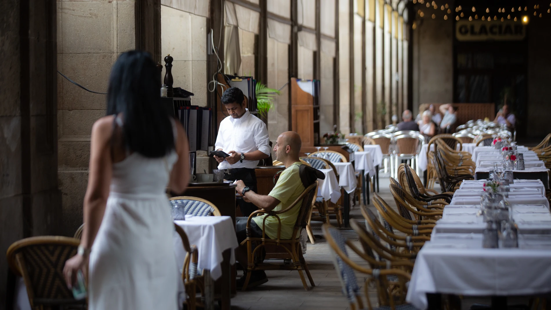 Un camarero atiende a una mesa en la plaza Real de Barcelona