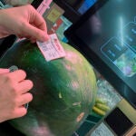 Un cliente pesa una sandía en un supermercado