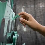 Una persona elige una papeleta en un colegio electoral
