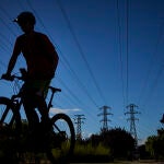 Unos ciclistas pasan junto a unas torres de alta tensión en la ciudad de Madrid