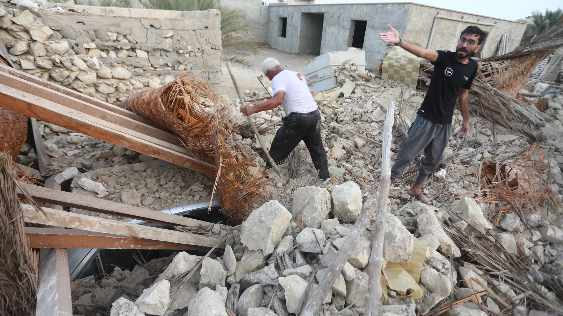 Dos hombres buscan entre los escombros provocados por el fuerte seísmo registrado en la provincia de Hormozgan en el sur de Irán