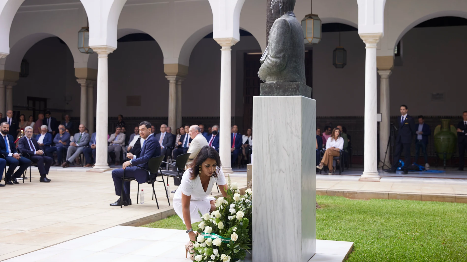 La presidenta del Parlamento, Marta Bosquet, realiza la ofrenda de flores durante el acto institucional del Parlamento andaluz en conmemoración del nacimiento de Blas Infante en el Parlamento, con Juanma Moreno al fondo. Joaquín Corchero / Europa Press