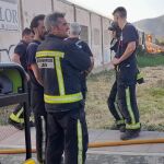 Bomberos con el incendio de la nave al fondo