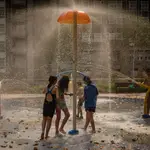 Varios niños se refrescan con una fuente de un parque público, este jueves en Ourense
