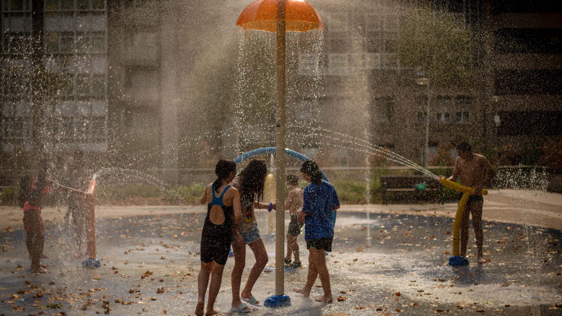Varios niños se refrescan con una fuente de un parque público, este jueves en Ourense