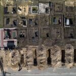 Un trabajador de un cementerio junto a las tumbas de civiles muertos en Bucha durante la guerra con Rusia, en las afueras de Kyiv