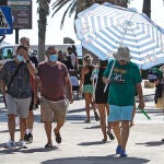 Un hombre se protege del intenso calor con una sombrilla de playa por las calles de la ciudad de Alicante.