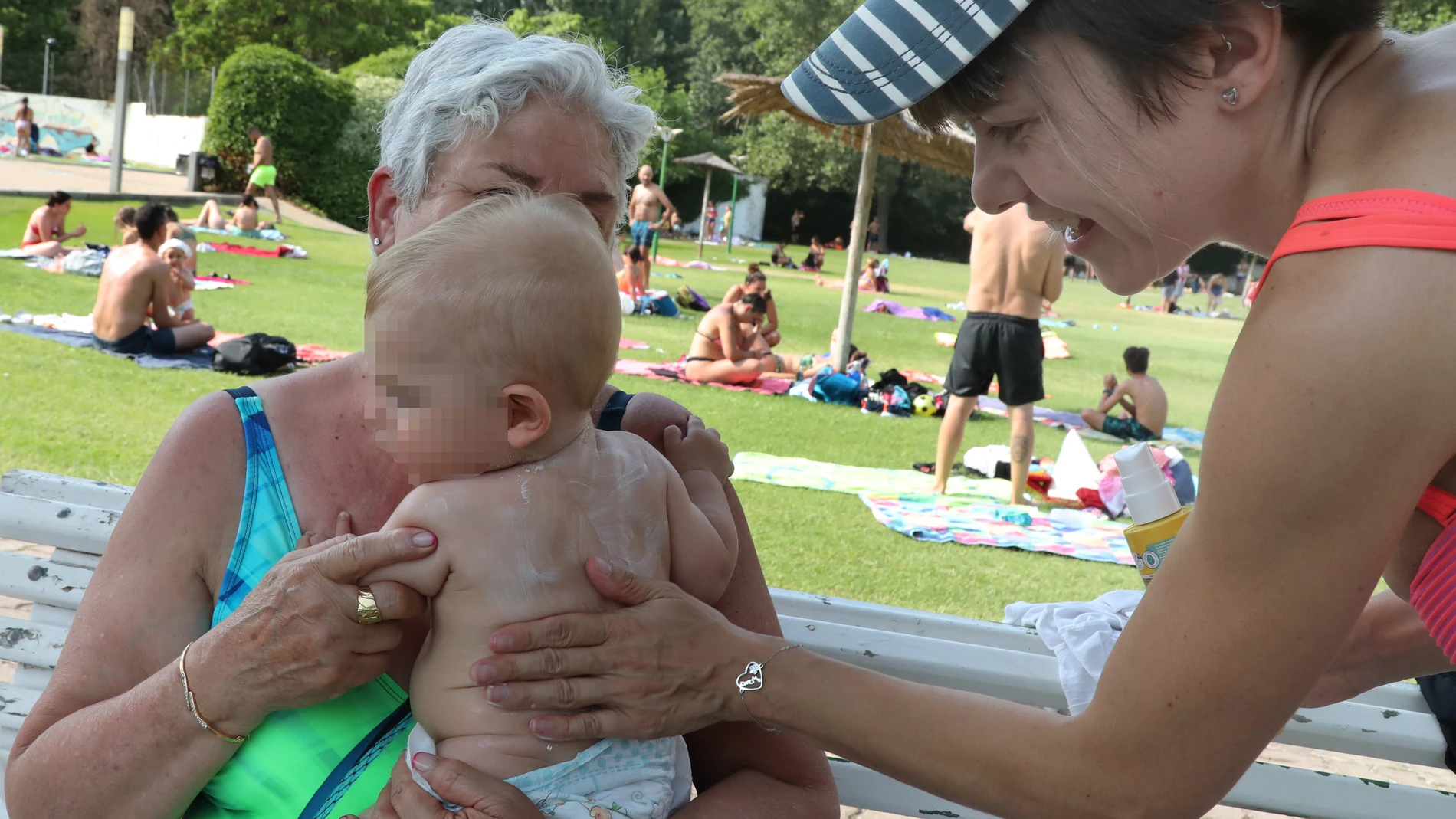 Una madre aplica crema solar a su bebé en una piscina de Palencia