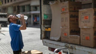 Un trabajador de una empresa de mudanzas bebe agua para combatir el calor en una calle del centro de Valencia