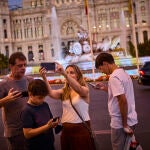 Turistas haciéndose selfies con su teléfono móvil en la plaza de la Cibeles