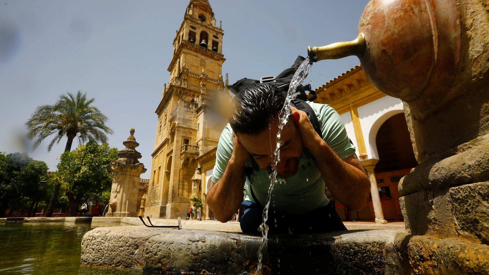 Un turista se refresca en una de las fuentes del patio de los naranjos de la Mezquita-Catedral de Córdoba