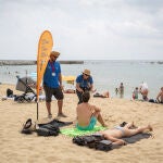 Dos informadores conversan de la nueva prohibición de fumar con bañistas, en la playa del Bogatell, en Barcelona