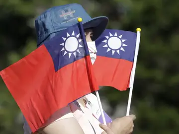 Una mujer sostiene varias banderas de Taiwán durante la fiesta nacional Una mujer sostiene varias banderas de Taiwán durante la fiesta nacional