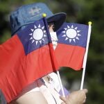 Una mujer sostiene varias banderas de Taiwán durante la fiesta nacional