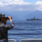 Un soldado miembro del Ejército Popular de Liberación (China) observa a través de unos prismáticos durante unos ejercicios militares mientras se ve la fragata Lan Yang de Taiwán