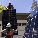 Dos trabajadores instalan paneles solares. (Jessica Christian/San Francisco Chronicle via AP)