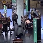 El agresor, arrestado por las autoridades, pasa por delante del cuerpo del escritor, que es atendido en el suelo