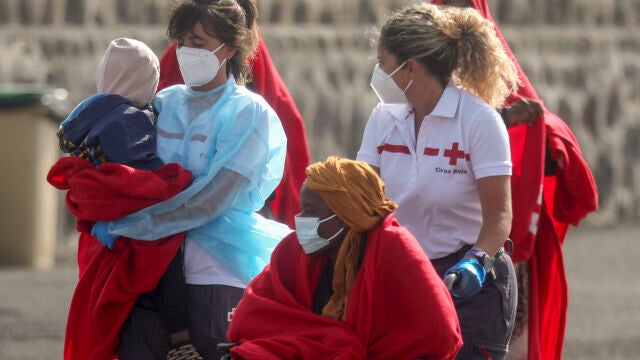 -FOTODELDÍA- ARRECIFE (LANZAROTE), 13/08/2022.- Una miembro de la Cruz Roja envuelve a un menor en una manta tras la llegada de una embarcación neumática con 51 inmigrantes a bordo, cuatro de ellos menores, al muelle de La Cebolla, Arrecife (Lanzarote), después de ser rescatada por Salvamento Marítimo cuando navegaba a unas 36 millas de Arrecife este sábado. EFE/Adriel Perdomo