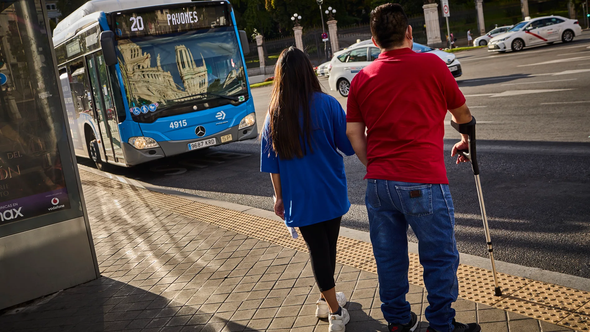 Dos usuarios del transporte público en una parada de la EMT en Madrid
