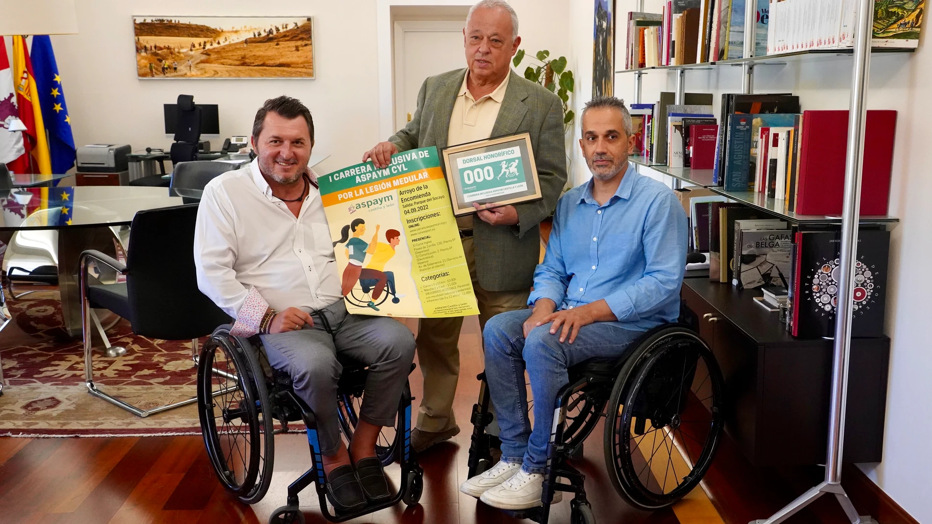 El consejero de Cultura, Turismo y Deporte, Gonzalo Santonja, recibe el dorsal solidario de la I Carrera inclusiva por la lesión medular, de manos de Ángel de Propios y Francisco Sardón