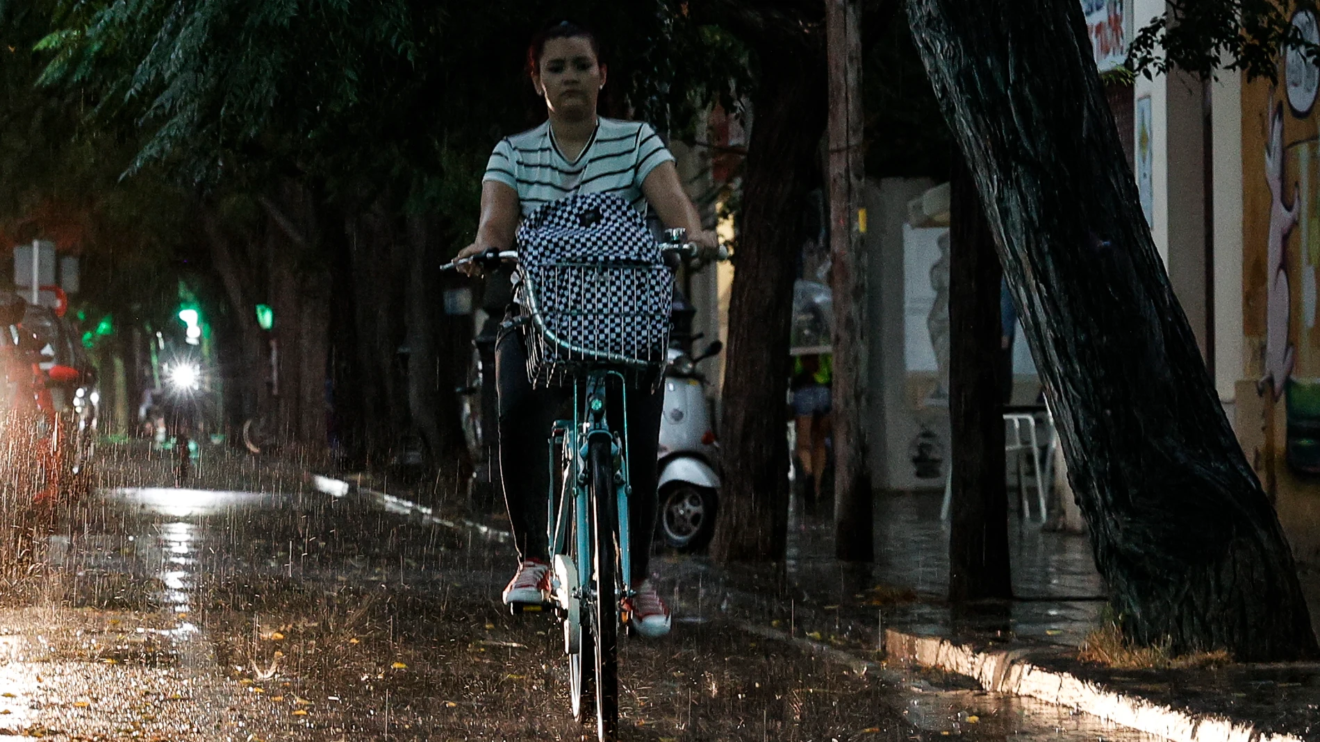 Una ciclista circula por un carril bici este jueves tarde bajo la tormenta que ha sorprendido a muchas personas