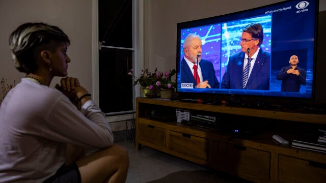 Una mujer mira por televisión el primer debate de las elecciones presidenciales de 2022 en Brasilia (Brasil). El presidente brasileño, Jair Bolsonaro, atacó este domingo a su principal rival en las elecciones, el expresidente Luiz Inácio Lula da Silva