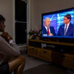 Una mujer mira por televisión el primer debate de las elecciones presidenciales de 2022 en Brasilia (Brasil). El presidente brasileño, Jair Bolsonaro, atacó este domingo a su principal rival en las elecciones, el expresidente Luiz Inácio Lula da Silva