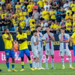 Los jugadores del Barcelona y el Cádiz esperan en el césped, preocupados por lo que sucede en la grada