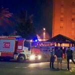 Dos agentes de las fuerzas de seguridad vigilan los alrededores tras prenderse fuego el chiringuito de una piscina de una urbanización