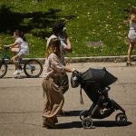 Familias con sus carritos de bebe pasean por el Retiro madrileño