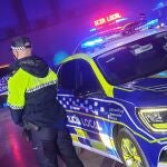 En primer término, un agente de espaldas, junto a un vehículo de la Policía Localde Sevilla