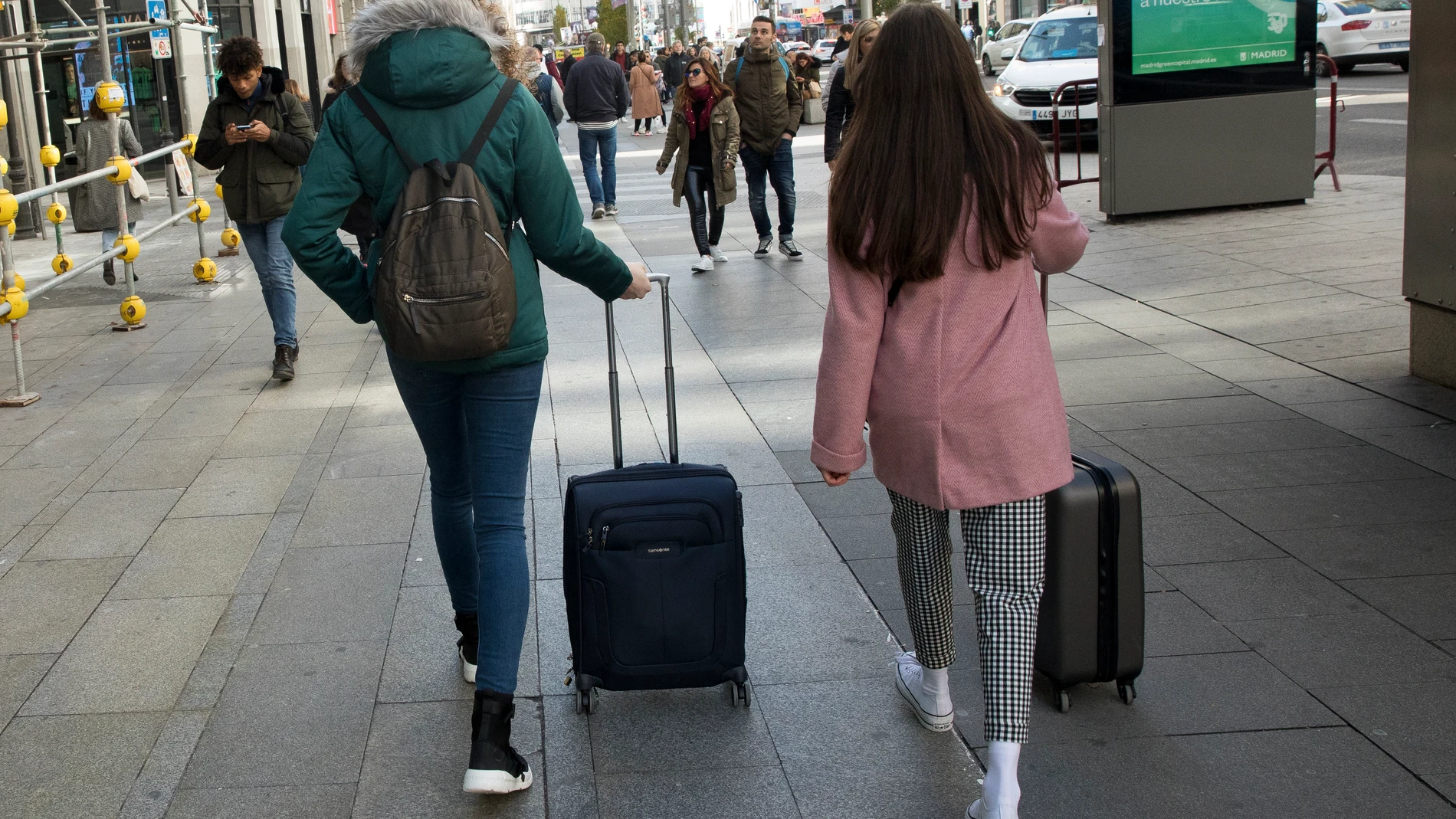 Personas con maletas buscando su reserva de piso turístico