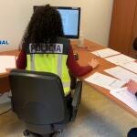 Una agente de la Policía inspeccionando documentación en un ordenador