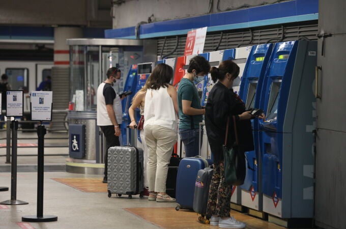 Varias personas recargan sus abonos de metro en la estación de Metro de Atocha, en Madrid