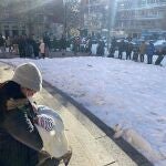 Una madre con su hijo, en primer plano, con una cola de personas al fondo, para recibir ayuda