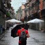 Un hombre se protege de la lluvia que cae en Alcalá de Henares