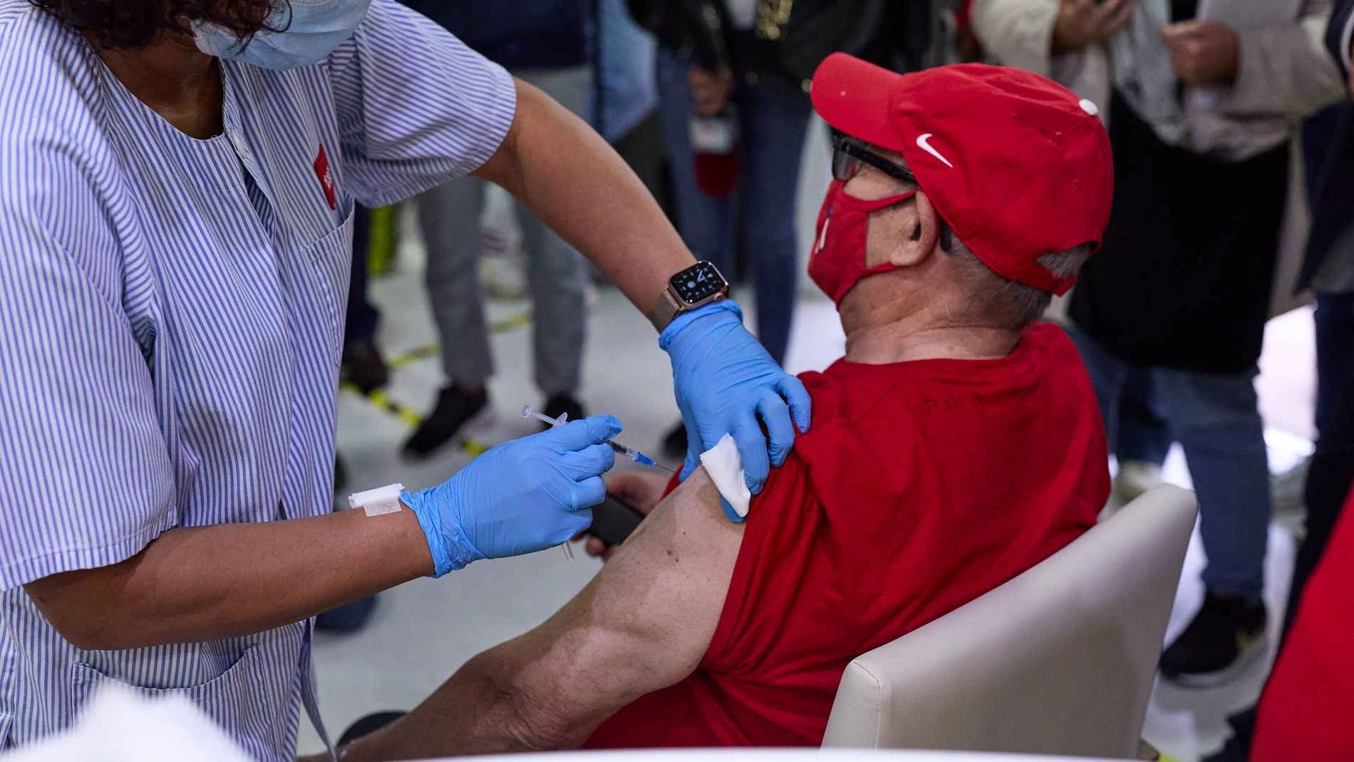 Una sanitaria vacuna a un hombre en una residencia de mayores de Madrid