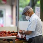Imagen de una persona mayor comprando en una frutería