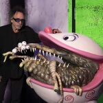 El cineasta Tim Burton posa junto a uno de sus bocetos exclusivos e inéditos presentes en la exposición
