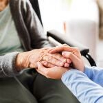 Enfermera sosteniendo ambas manos de una mujer mayor.