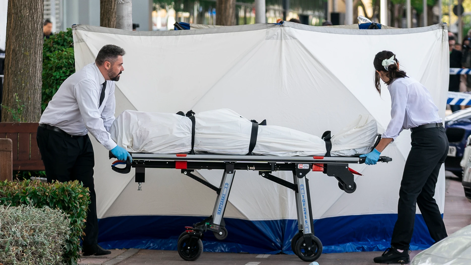 Dos trabajadores de la funeraria levantan el cadáver del joven asesinado en las inmediaciones de la discoteca "Caña Brava"