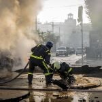 Un bombero ayuda a su compañero a salir de un agujero dejado por el impacto de los misiles en Kyiv