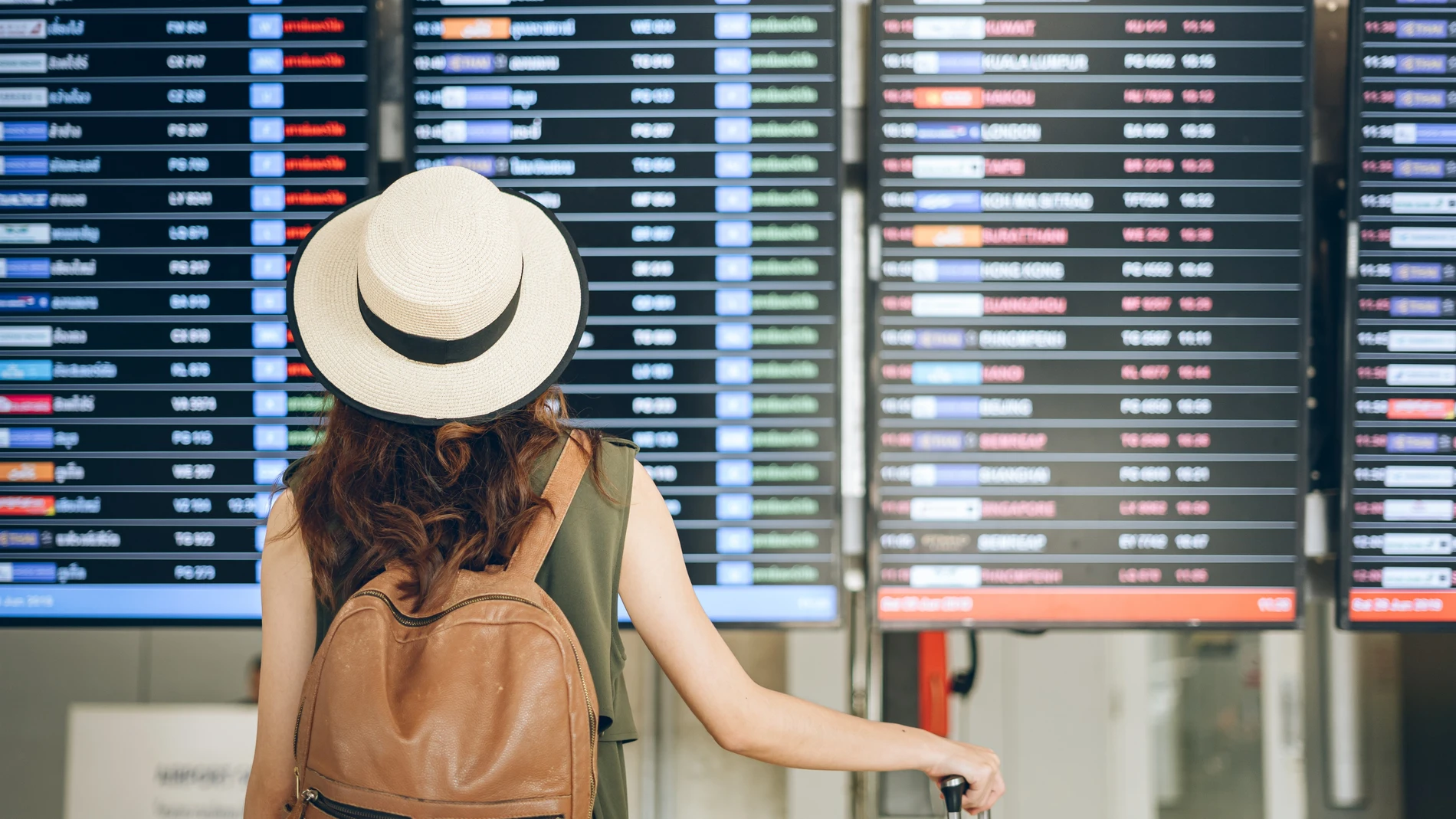 Una pasajera viendo el panel de vuelos en un aeropuerto