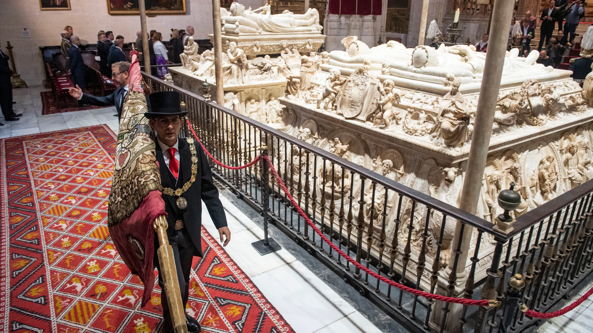 El alcalde de Granada, Francisco Cuenca, tremola el estandarte real ante las tumbas de los Reyes Católicos durante la celebración de una misa en la Capilla Real de Granada para celebrar el Día de la Hispanidad, este miércoles. EFE/ Miguel Ángel Molina